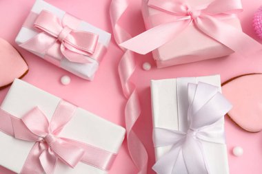 Pembe arka planda kurdeleli Noel hediyesi kutuları