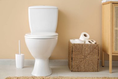 Tuvalette tuvalet deliğinin yanında rulo kağıt olan bir sepet.