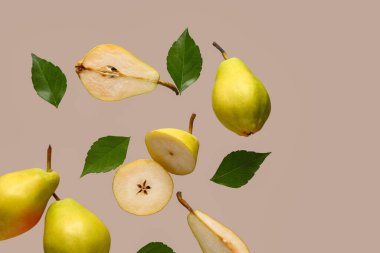 Gri arka planda taze armut ve yapraklar uçuşuyor.