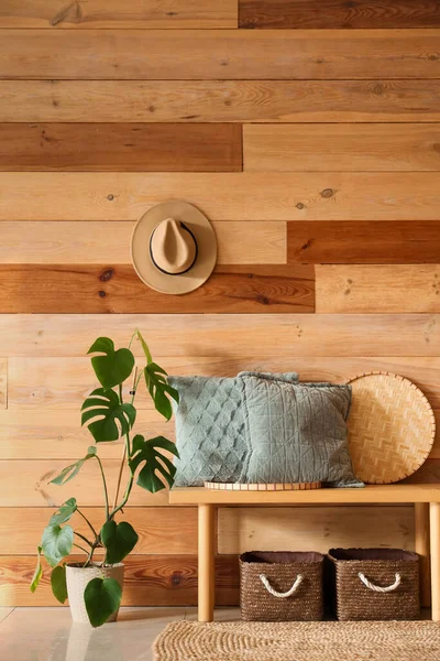 Yastıklı bank, hasır hasırlar ve odasındaki ahşap duvarın yanındaki saksı bitkisi.