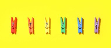 Sarı arka planda renkli mandallar. LGBT kavramı