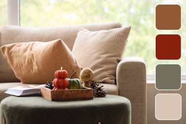 İçinde yanan mum, kitap ve sonbahar süsleri olan ahşap tepsi oturma odasının içinde. Farklı renk desenleri