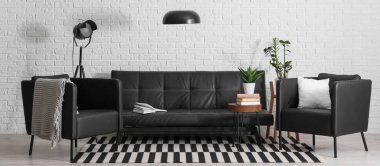 Siyah deri kanepe, sehpa, koltuk ve lambalar oturma odasında.