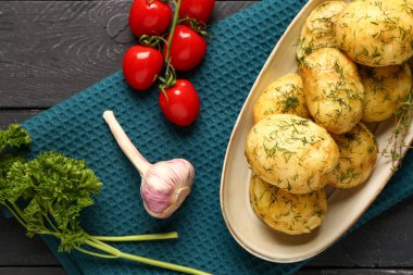 Bir tabak haşlanmış patates, dereotlu ve ahşap kaplama domatesli.