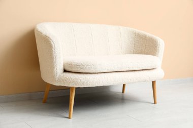 Bej duvarın yanındaki rahat beyaz kanepe.