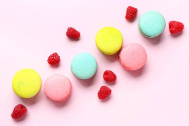 Farklı tatlı badem kurabiyeleri ve pembe arka planda ahududular.