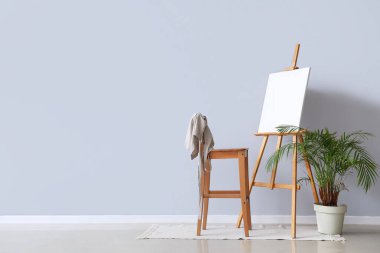 Gri duvarın yanında boş tuval olan ahşap sehpa