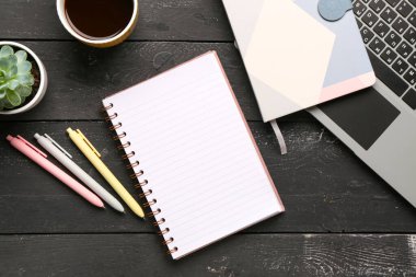 Laptoplu defterler ve siyah ahşap arka planda bir fincan lezzetli kahve.