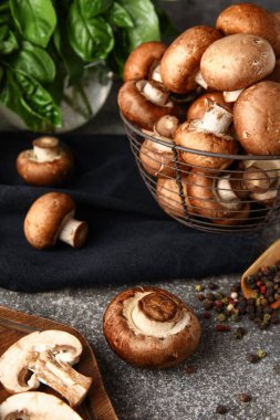 Fesleğenli taze mantar sepeti ve gri arka planda biber.