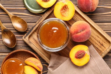 Tatlı şeftali reçeli kavanozu ve ahşap arka planda taze meyveler içeren kompozisyon, yakın plan.