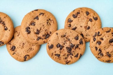 Mavi arka planda çikolata parçacıklı lezzetli kurabiyeler.