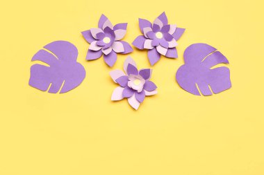 Renkli origami çiçekleri ve sarı arkaplanda yapraklar