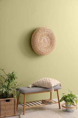 Yastıklı gri bank ve yeşil duvarın yanında bitkiler