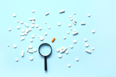 Büyüteç ve mavi arka planda bir sürü farklı hap.