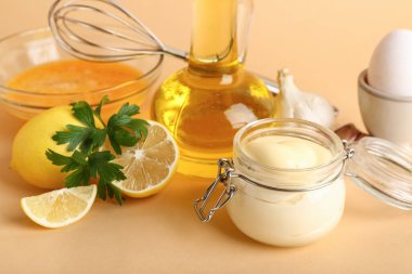 Taze mayonez kavanozu ve bej arka planda malzemeler.