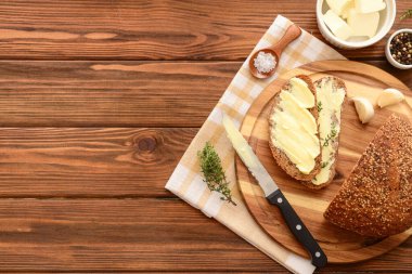 Taze ekmek, farklı baharatlar ve ahşap arka planda bir kase tereyağı.