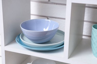 Beyaz tuğla duvarın yanında temiz sofra takımı olan raf ünitesi