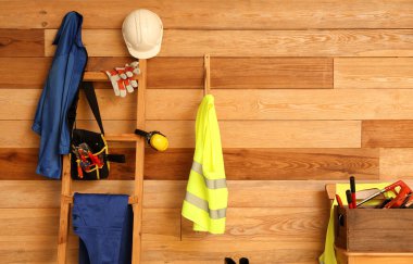 Güvenlik yelekleri, üniforma ve ahşap duvarın yanındaki aletler.