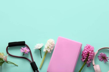 Renkli arka planda spor ekipmanları, kulaklıklar ve çiçeklerle kompozisyon