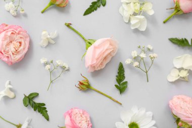 Gri arkaplanda çiçekli ve yeşil yapraklı güzel kompozisyon, yakın plan.