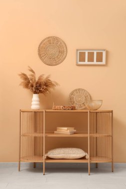 Bej duvarın yanında farklı dekorları olan ahşap raf ünitesi.