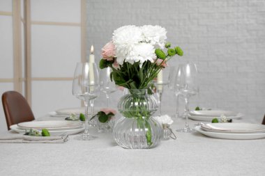 Yemek odasındaki beyaz tuğla duvarın yanında düğün kutlaması için masa hazır.