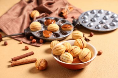 Lezzetli ceviz şeklindeki kurabiyelerle bej masanın üzerinde haşlanmış süt, yakın plan.