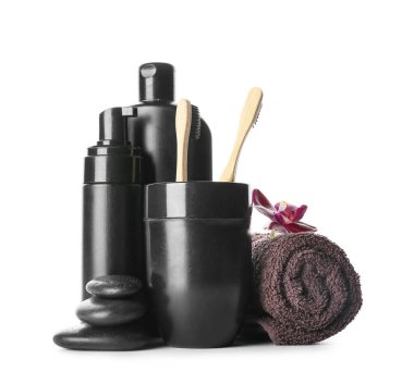 Beyaz arka planda banyo aksesuarları ve siyah spa taşları.