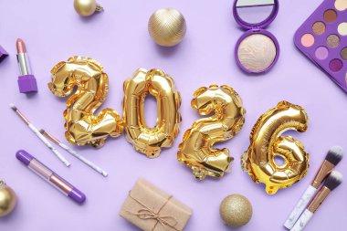 Makyaj ürünleri ve eflatun arkaplanlı Noel toplarıyla 2025