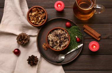 Bir kase geleneksel Ukrayna Kutya yemeği ve bir sürahi Uzvar ve ahşap arka planda yanan mumlar.