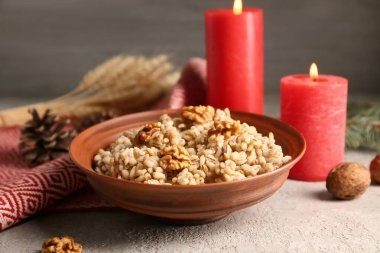 Bir kase geleneksel Ukrayna Kutya yemeği ve beyaz masada yanan mumlar.