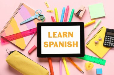 Pembe zemin üzerinde tablet ve hesap makinesi olan farklı bir kırtasiye.