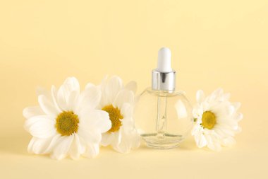 Renk zemininde papatya çiçekleri olan bir şişe gerekli yağ.