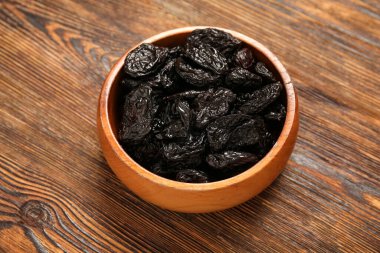 Ahşap arka planda lezzetli kurutulmuş erikli kase