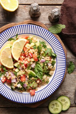 Ahşap arka planda lezzetli tabakta salata.