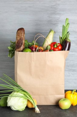 Siyah masanın üzerinde farklı ürünler olan kağıt torba.