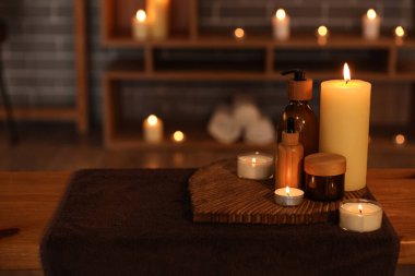 Koyu kaplıca salonundaki masada mum yakan kozmetik ürünleri, yakın plan.