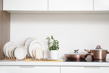 Mutfaktaki beyaz tezgahın yanında farklı temiz bulaşık takımları var.