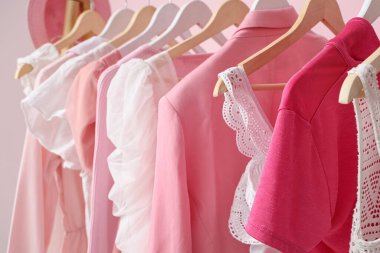 Pembe duvarın yanında asılı giysilerle dizilin, yakın plan.