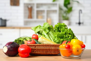 Tahta mutfak tezgahında farklı taze sebzelerle dolu bir sepet.