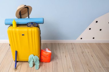 Mavi duvarın yanında toplanmış bavullar ve plaj aksesuarları.