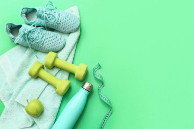 Yeşil arka planda elma, spor ayakkabısı, havlu ve spor malzemeleri