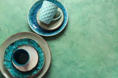 Temiz tabaklar, tabaklar ve fincanlar yeşil grunge arka planda. Üst görünüm