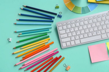 Klavye ve turkuaz arka planda farklı kalemlerle grafik tasarımcısının çalışma yeri