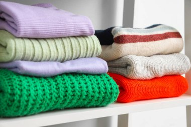 Soyunma odasında şık kazaklı raflar, yakın plan.