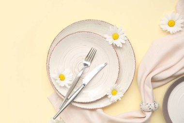 Sarı arka planda güzel beyaz kasımpatı çiçekleri olan şık masa ayarı