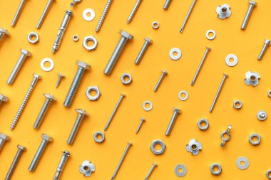 Turuncu arka planda farklı musluk cıvataları, vidalar ve krom fındıklar düzenleme