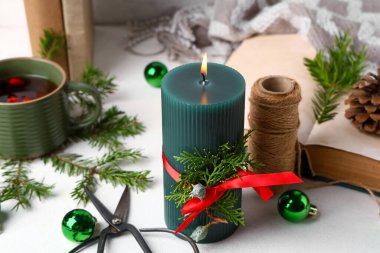 Noel toplarıyla yanan mum ve beyaz masanın üzerinde çam dalları, yakın plan