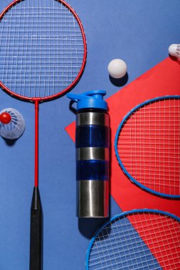Renkli arka planda bir şişe su, raket, top ve mekik sikli kompozisyon