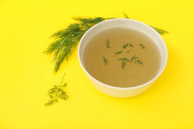 Sarı arka planda bir kase lezzetli sebze suyu.
